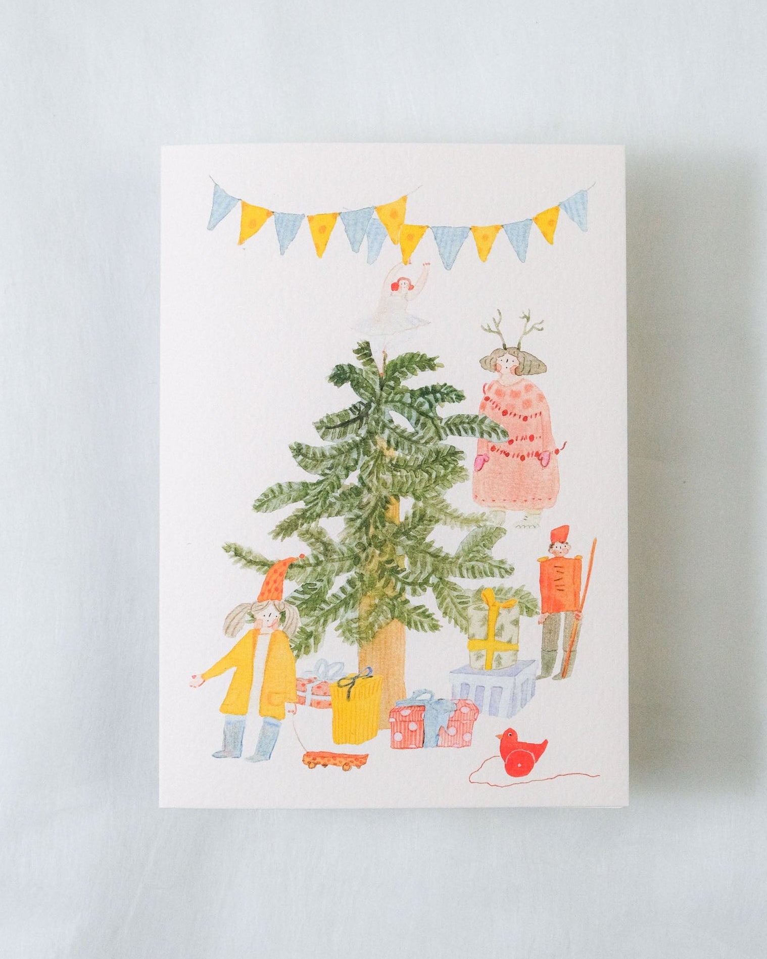 Card with a festive illustration of people around a Christmas tree on a white background